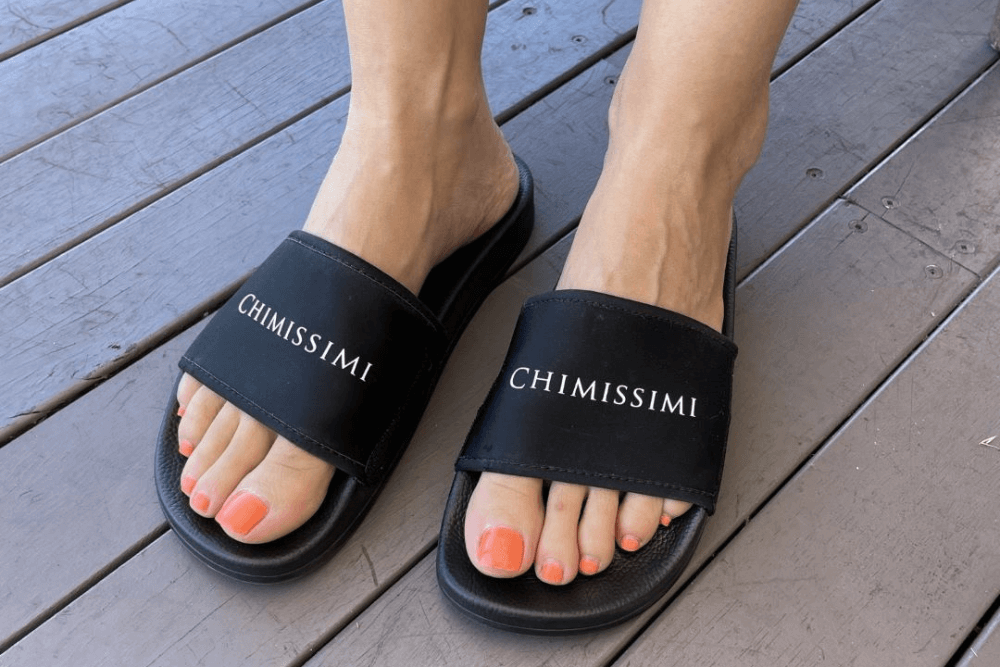 Woman wearing Chimissimi black base slides with white Chimissimi branding