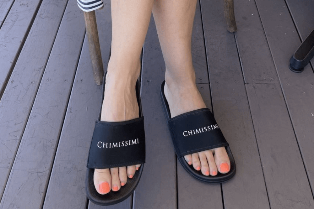 Woman wearing black base Chimissimi slides with white Chimissimi branding