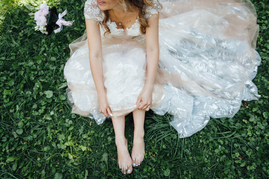 Barefoot bride sitting on a patch of grass