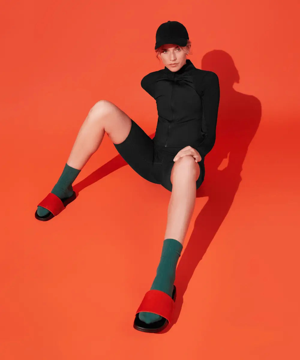Model wearing sporty outfit and black slides with red upper made of real cow fur.