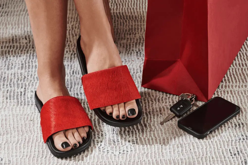 Model wearing black slides with red upper made of real cow fur.
